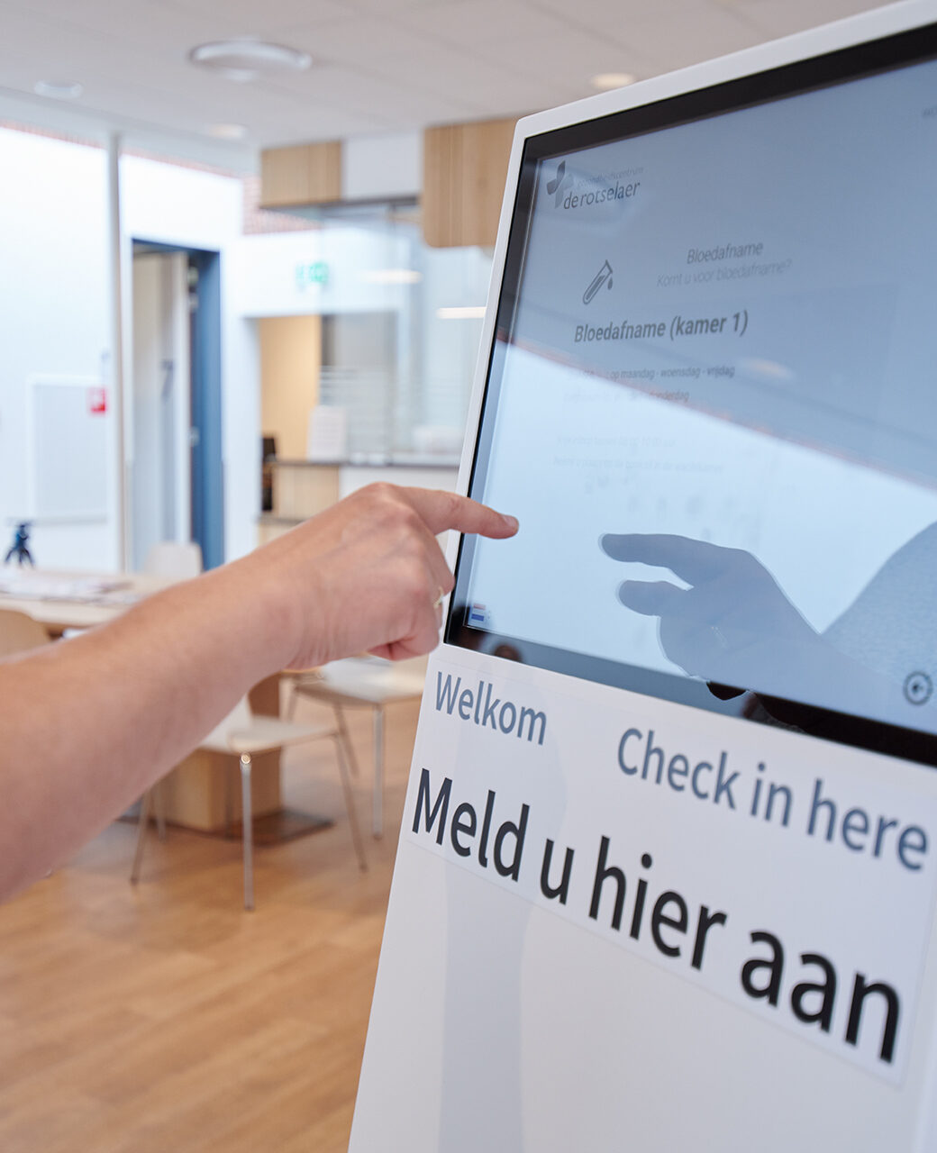 Een patiënt meldt zich aan bij de aanmeldzuil in de wachtruimte