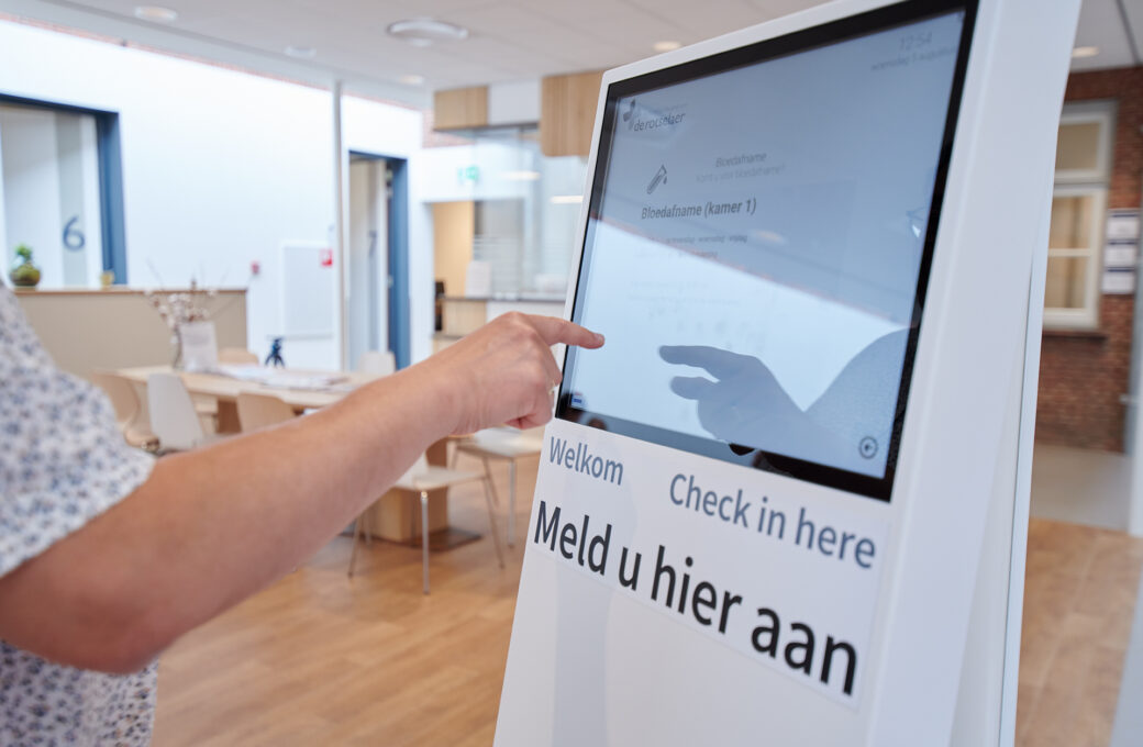 Een patiënt meldt zich aan bij de aanmeldzuil in de wachtruimte