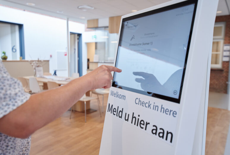Een patiënt meldt zich aan bij de aanmeldzuil in de wachtruimte
